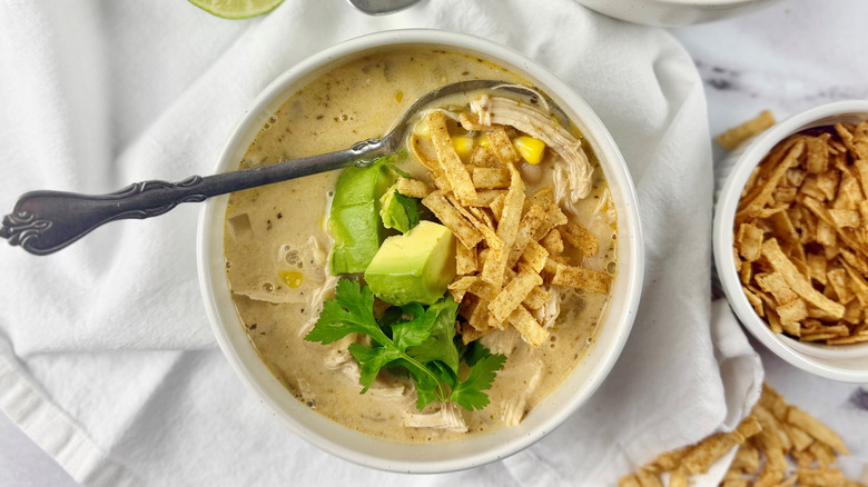 bowl of chicken chili with sliced avocado and cilantro