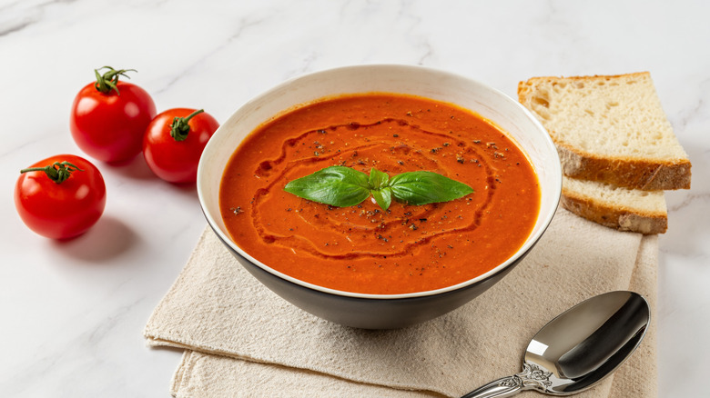 A bowl of tomato soup with olive oil and basil as a garnish