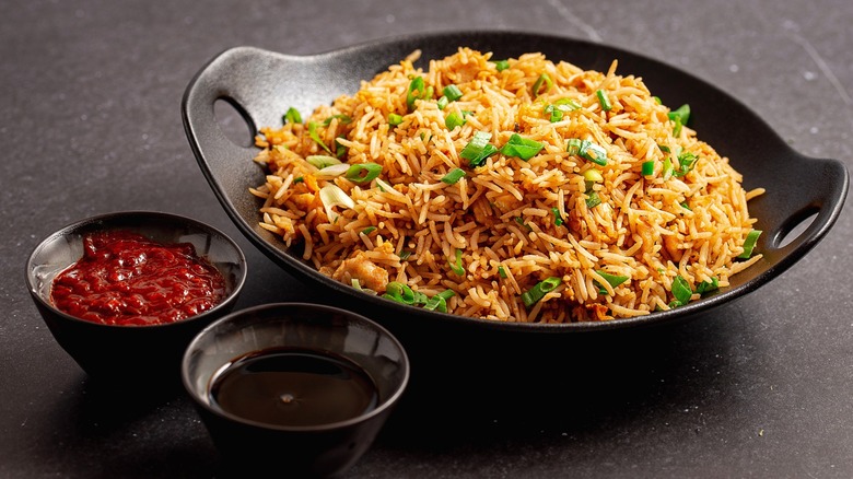 Fried rice in black dish with sauces on the side