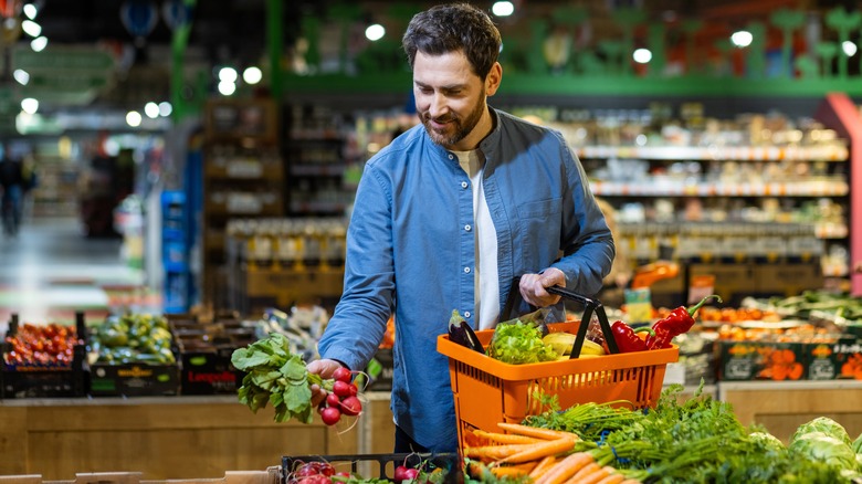 A man selecting vegetables at a grocery store