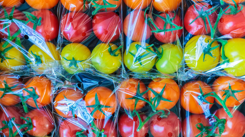 Colorful tomatoes wrapped in plastic wrap stacked next to each other.