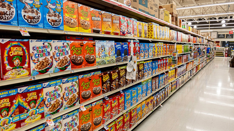 Cereal aisle at a grocery store, with Cinnamon Toast Crunch, Reeses Puffs, and more brands