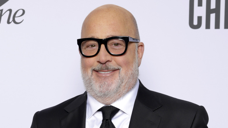 Andrew Zimmern smiling wearing a black suit and black tie at a red carpet event