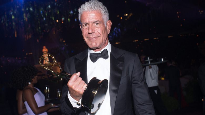 Anthony Bourdain holding an Emmy in a tuxedo during the event.