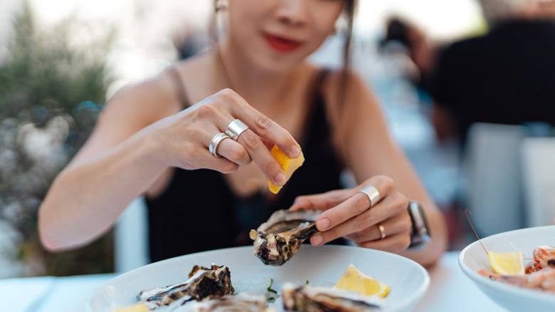 Woman squeezes a lemon over an oyster