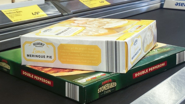 A double pepperoni pizza and lemon meringue pie on conveyor belt at Aldi checkout.