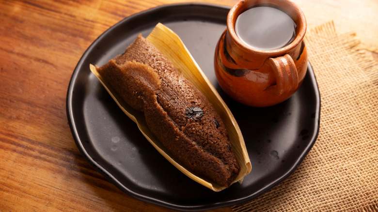 Homemade Mexican tamale on a plate with a hot drink