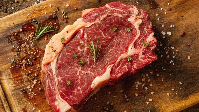 A ribeye steak on a wooden cutting board.