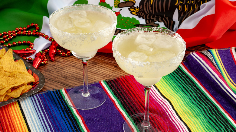 Two classic margaritas on a table with a Mexican flag