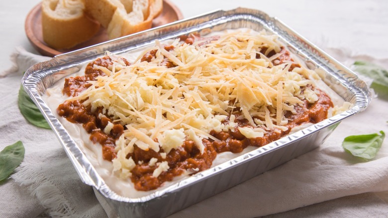 A frozen lasagna, not yet heated up that is sitting on a counter.