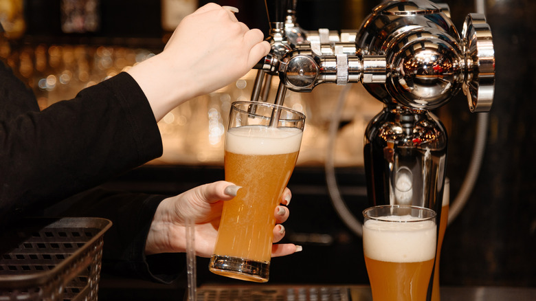 A bartender pouring beer from a tap.