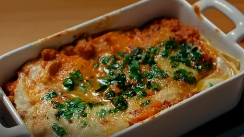 close-up of Bobby Flay's lasagna on "Beat Bobby Flay" topped with browned melted cheese, oil, and herbs in a white dish