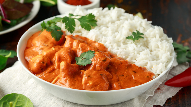 A bowl of chicken tikka masala served with white rice.
