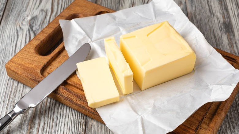 A slab of butter sliced on a wooden board.