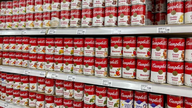 Campbell's soup cans displayed on a supermarket shelf.