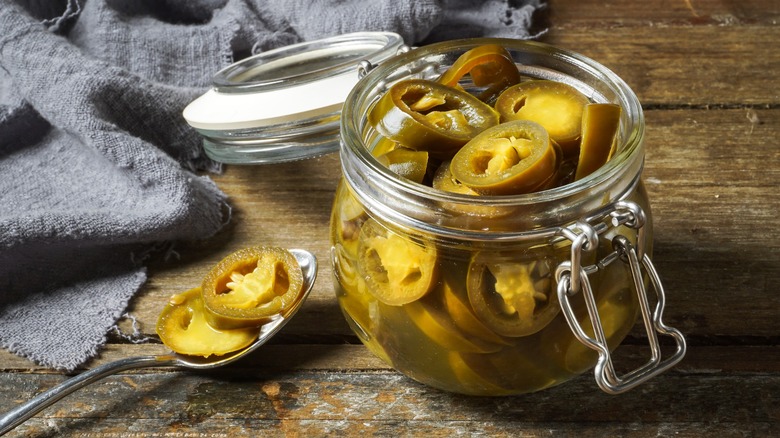 Pickled jalapeños in glass jar and on spoon
