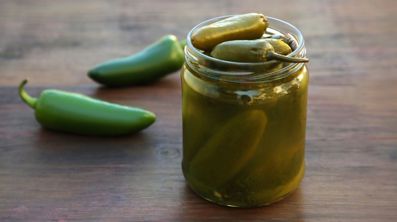 Fresh and pickled jalapeños on an old wood table