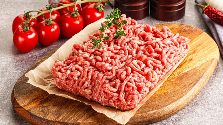Ground beef on brown paper with herbs and fresh tomatoes