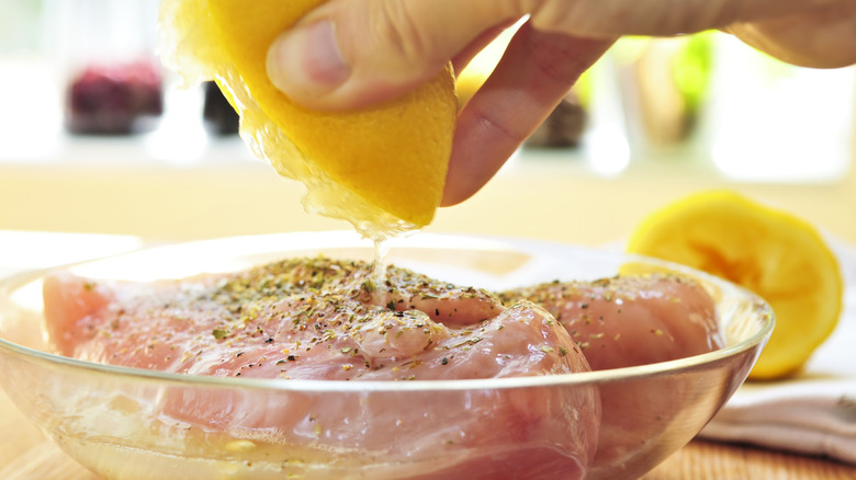Squeezing fresh lemon juice over raw chicken breasts