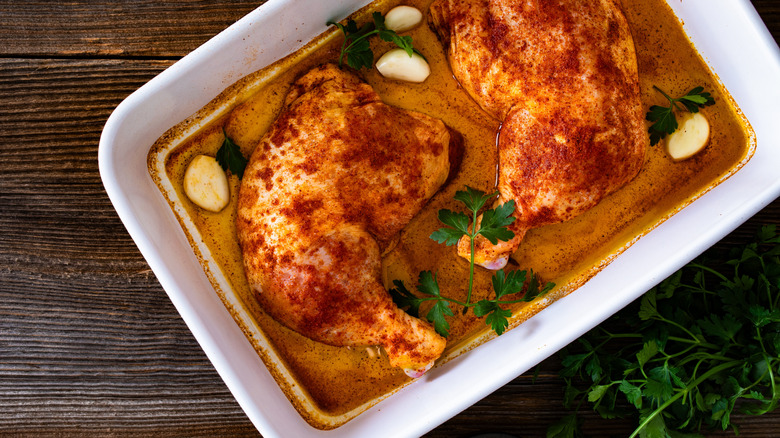Raw marinated chicken leg quarters in baking dish