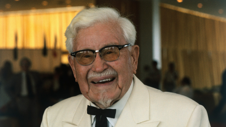KFC founder Colonel Harland Sanders smiles in white suit and black bowtie