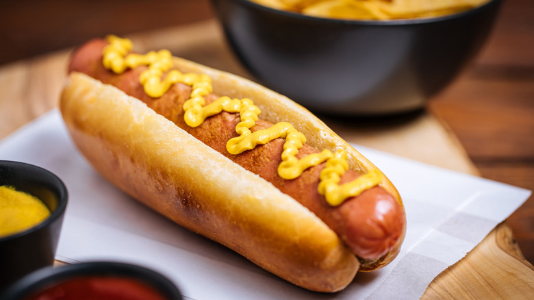 A hot dog in a bun on white parchment bag
