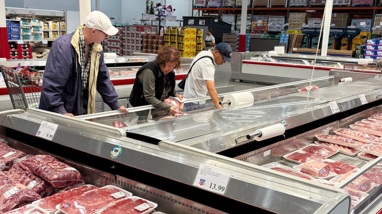 People shopping for meat at Costco.