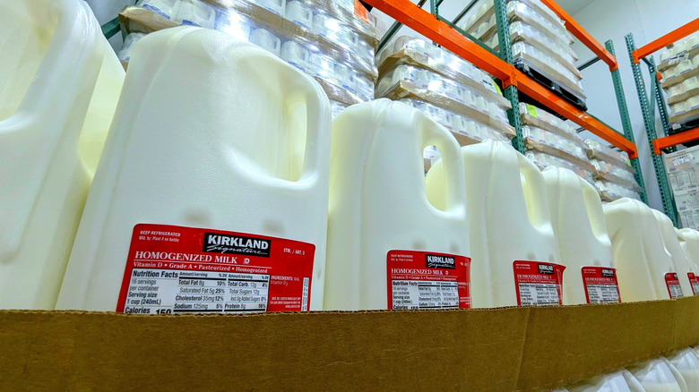 A row of Kirkland milk jugs in Costco on cardboard pallets