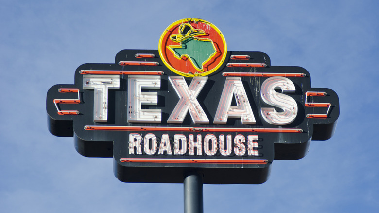 A Texas Roadhouse sign standing during the day.