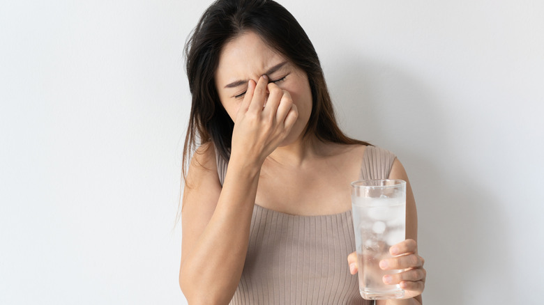 A woman pinches her brow after drinking ice water