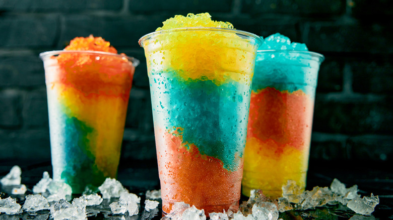 Three multicolored frozen drinks with crushed ice