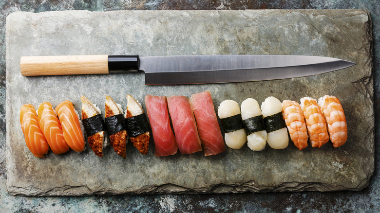 Professional Japanese knife on a stone slab with various sashimi