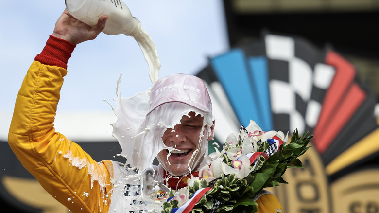 Josef Newgarden celebrating his Indy 500 win by pouring a bottle of milk on his head.