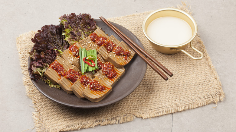 Korean acorn jelly with red sauce on plate with chopsticks
