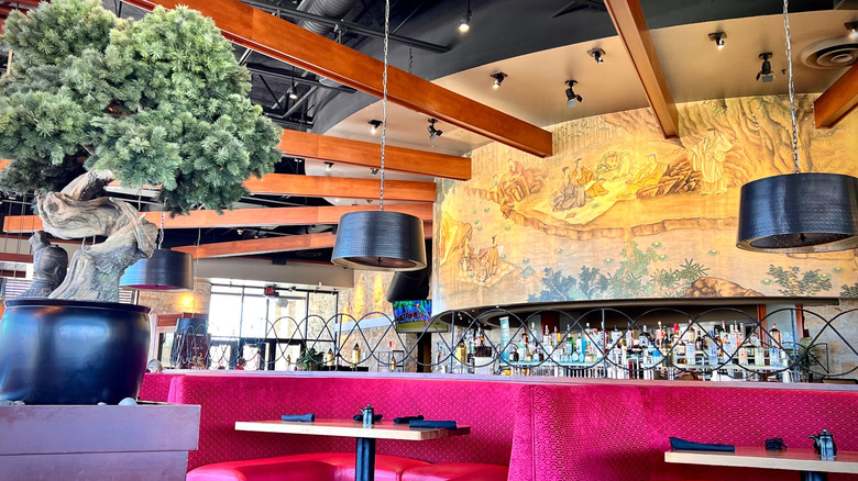 The modern interior of a P.F. Chang's with golden traditional mirror behind the bar and a bonsai tree