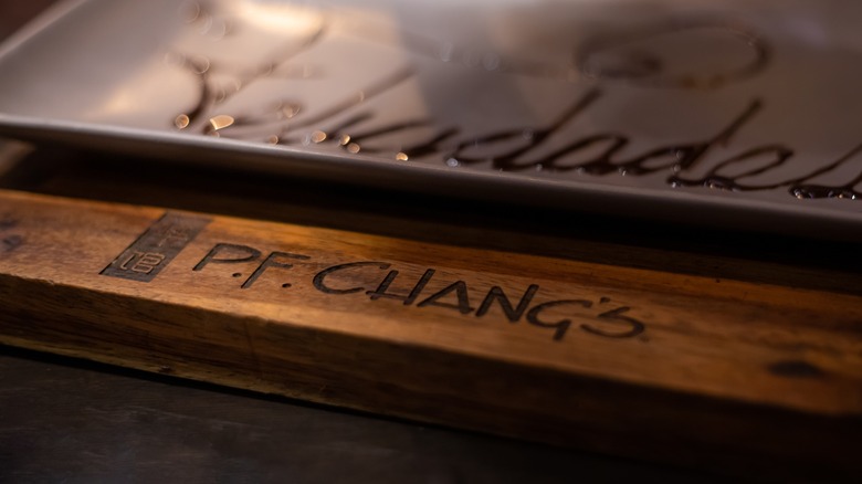 Brown plate with chocolate writing behind a wooden P.F. Chang's chopstick rest