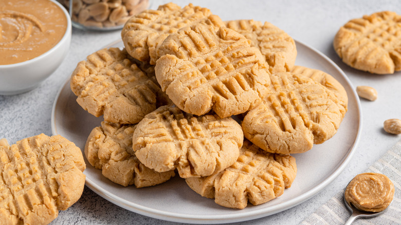 Plate of baked peanut butter cookies next to bowl of peanut butter