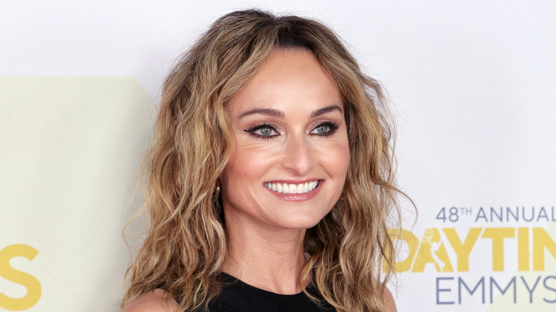 Candid picture of Giada De Laurentiis in front of white background with yellow writing