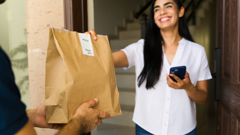 woman accepts grocery delivery at front door