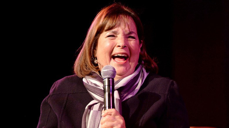 Ina Garten laughing on stage with microphone in hand.