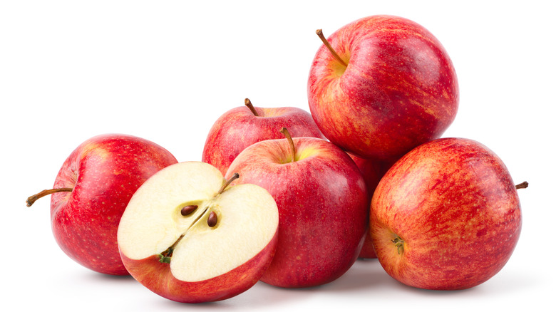 A loose pile of apples, including one cut in half