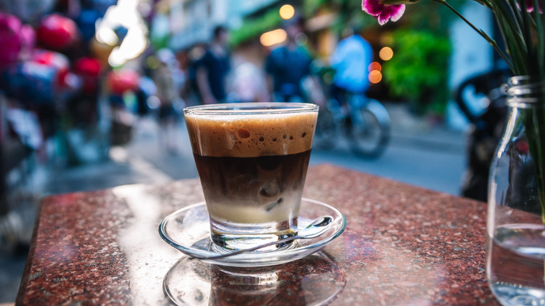A cup of Vietnamese coffee on a table near a busy street