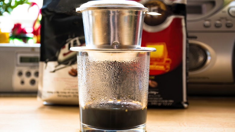 Phin brewer on top of a glass to brew a cup of Vietnamese coffee