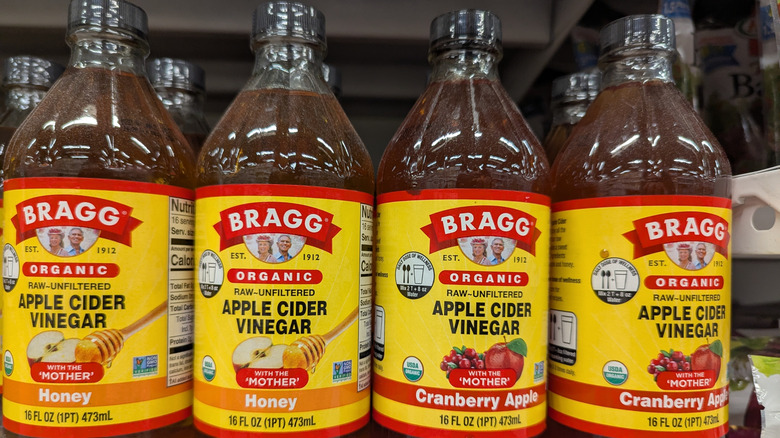 Bottles of Bragg apple cider vinegar sitting on a grocery store shelf.
