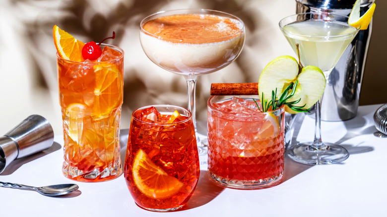 Colorful cocktails in faceted glasses with barware