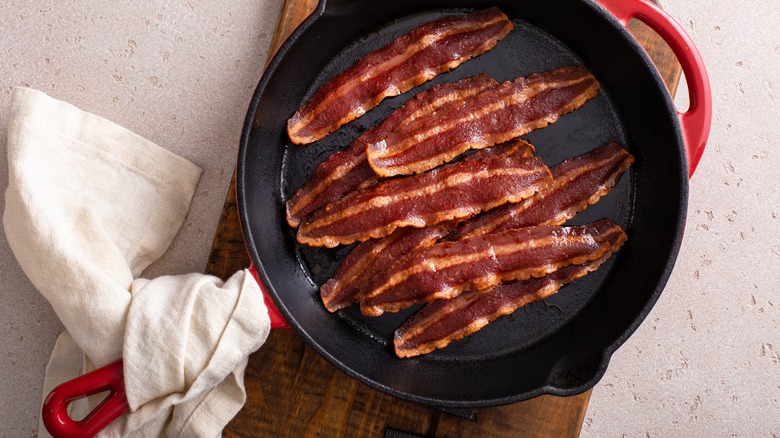 cooked bacon in cast iron skillet with towel