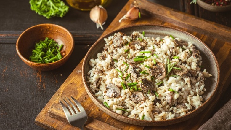 Risotto with mushrooms and herbs on a wooden board.