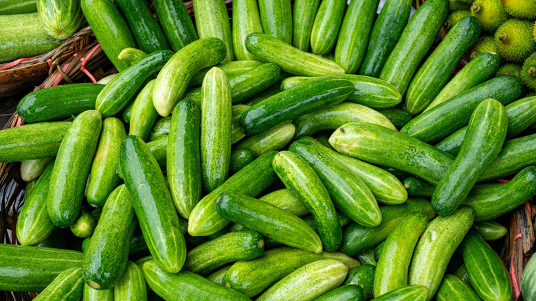 A loose pile of cucumbers in a wicker basket