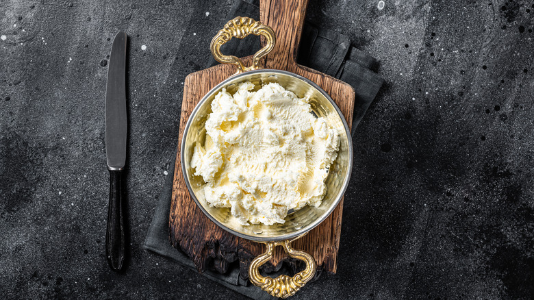 Fresh butter in bowl on board next to knife