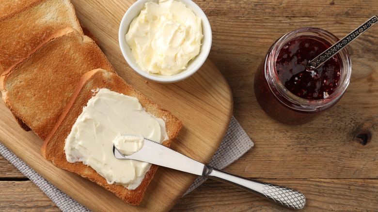 Toasted bread spread with butter with jar of jam